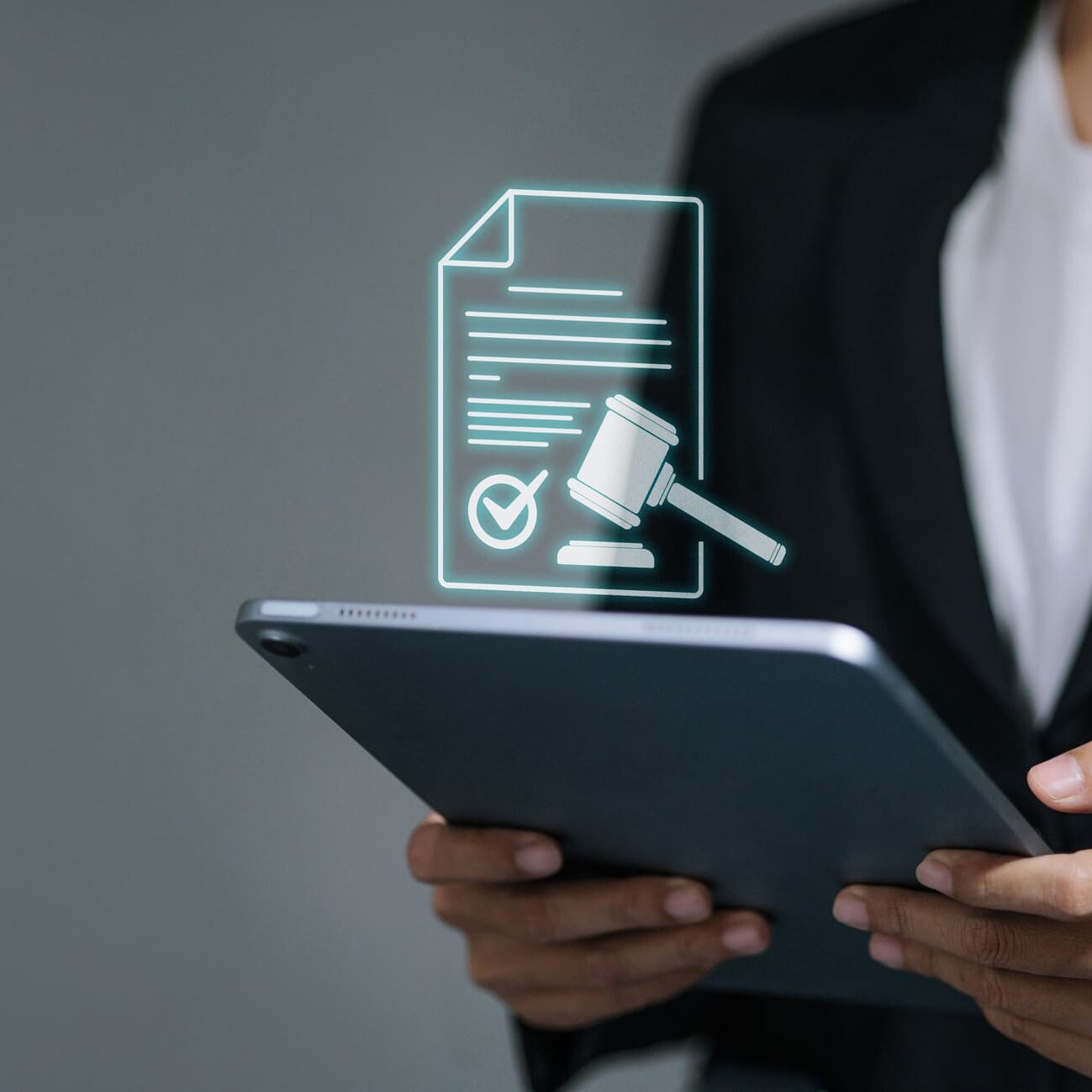 Business person holding a tablet with a virtual legal document icon featuring a gavel and checkmark. Concept of digital contracts, e-signatures, court verdicts, and lawtech.